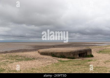 Una pillbox per mitragliatrici Vickers della seconda guerra mondiale, metà sepolta sulla spiaggia di Cudmore Grove, East Mersea, Mersea Island, Essex. Foto Stock