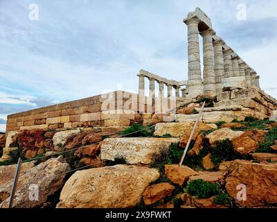 37 km a sud di Atene, il tempio greco Poseidone si trova lungo la penisola dell'Attica. È visibile a tutti i marinai di passaggio e funge da faro per gli Ateniesi in mare. Il tempio vicino all'oceano era un luogo appropriato per Poseidone, il dio del mare e delle tempeste, e uno degli dei greci più malvagi, pigri e avidi. Il tempio è stato costruito nel 444 a.C. ed è un luogo popolare per ammirare un tramonto, che potrai ammirare attraverso le sue antiche colonne mentre il sole si tuffa nel Mar Egeo. Grecia. Foto Stock