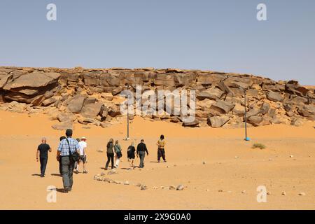 Turisti che visitano un sito archeologico per vedere i petroglifi a Taghit, nell'Algeria occidentale Foto Stock