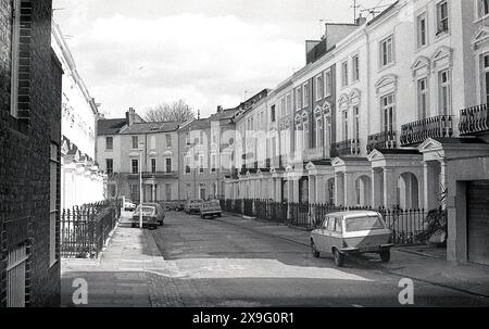 1970, storica, vista delle case cittadine terrorizzate georgiane in una strada secondaria dietro Regent Park Rd, nella zona di Primrose Hill nel borgo londinese di Camden, Inghilterra, Regno Unito. Alcune auto dell'epoca parcheggiavano sul marciapiede. Foto Stock