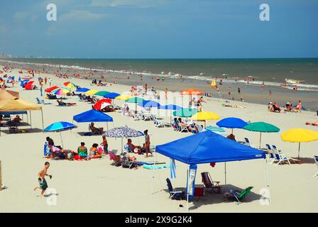 Gli amanti della spiaggia possono prendere la maggior parte della sabbia, seduti sotto gli ombrelloni lungo la riva di Myrtle Beach, South Carolina, in una giornata di vacanza estiva Foto Stock