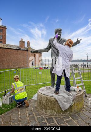 Lady conservazioniste che puliscono la statua di Billy Fury sul lungomare, Liverpool, Merseyside, Regno Unito, il 20 maggio 2024 Foto Stock