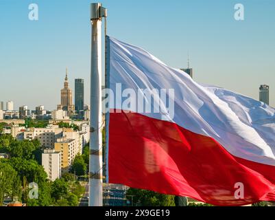Bandiera nazionale polacca bianca e rossa contro i grattacieli nel centro di Varsavia, paesaggio aereo sotto il cielo azzurro Foto Stock