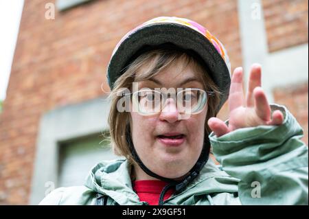 Ritratto all'aperto di una donna di 41 anni con la sindrome di Down che indossa un casco da ciclismo all'aperto, Tienen, Fiandre, Belgio. Modello rilasciato. Foto Stock