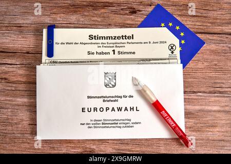 30 maggio 2024: Elezioni europee del 2024, schede elettorali per le elezioni in Baviera per l'Europa con busta cartacea per le votazioni postali su un tavolo con bandiera UE e penna a sfera da contrassegnare con il logo del partito di sinistra *** Europawahl 2024, Stimmzettel zur Wahl in Bayern für Europa mit Stimmzettelumschlag für die Briefwahl auf einem Tisch mit EU-Fahne und Kugelschreiber zum Ankreuzen mit dem Logo der Partei die Linke Foto Stock