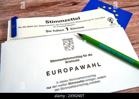 30 maggio 2024: Elezioni europee del 2024, scheda elettorale per le elezioni in Baviera per l'Europa con busta di carta per le votazioni postali su un tavolo con bandiera UE e penna a sfera da contrassegnare con il logo del partito al semaforo o del partito di governo Verde / Bündis 90 *** Europawahl 2024, Stimmzettel zur Wahl in Bayern für Europa mit Stimmzettelumschlag für die Briefwahl auf einem Tisch mit EU-Fahne und Kugelschreiber zum Ankreuzen mit dem Logo der Ampel-Partei bzw. Regierungs-Partei die Grünen / Bündis 90 Foto Stock