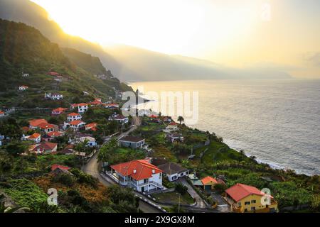 Il sole tramonta dietro le scogliere che torreggiano sopra Ponta Delgada, un piccolo villaggio sulla costa settentrionale dell'isola di Madeira (Portogallo) nell'Oceano Atlantico Foto Stock