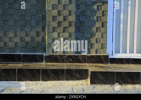 Forma astratta da un angolo dell'edificio e pavimento piastrellato, motivo quadrato, consistenza ruvida e liscia. Foto Stock