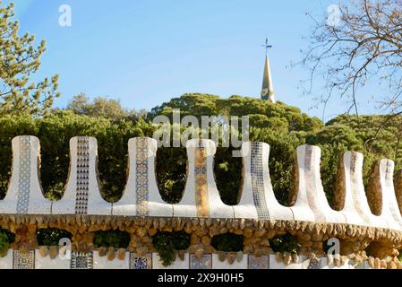 Antoni Gaudí, Parco Guell, Patrimonio dell'Umanità dell'UNESCO, Barcellona, Catalogna, Spagna, Europa, un muro decorativo con piastrelle a mosaico e alberi nella Foto Stock