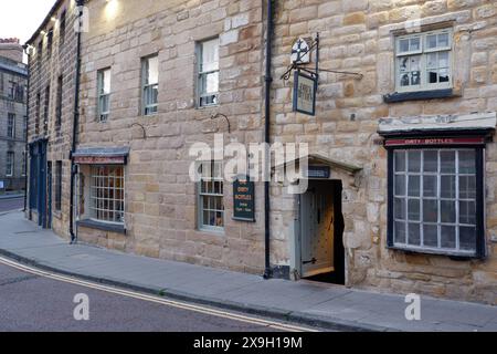 Il pub Dirty Bottles ad Alnwick, Northumberland. Si dice che le bottiglie nella finestra siano maledette e quindi non siano state toccate per 200 anni. Foto Stock