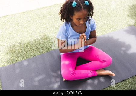 La ragazza birazziale pratica yoga all'aperto a scuola, con spazio per le copie Foto Stock