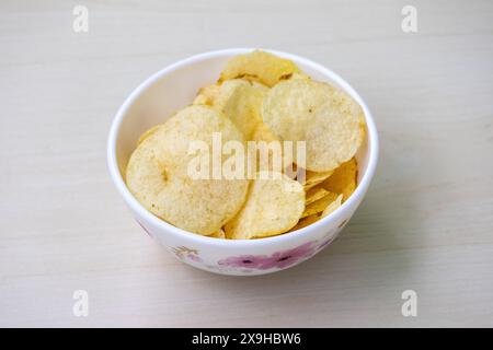 Una ciotola di patatine croccanti salate su fondo di legno. Foto Stock