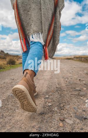 Una persona sta camminando su una strada sterrata indossando jeans e una scarpa marrone, viaggiando attraverso le ande peruviane. Foto Stock