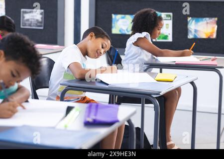 I bambini sono concentrati sul loro lavoro scolastico in una classe scolastica, sottolineando il concetto di istruzione Foto Stock