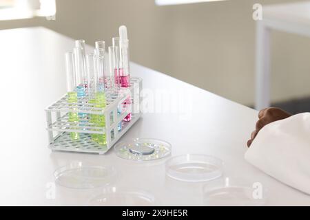 La mano di uno scienziato poggia vicino alle provette di un laboratorio, con spazio di copia Foto Stock