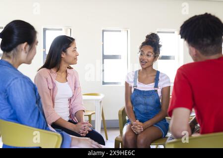 Studenti diversi si impegnano in una discussione di gruppo al liceo. L'ambiente promuove l'apprendimento collaborativo e l'interazione tra pari. Foto Stock