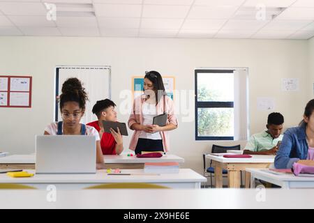 La giovane donna birazziale insegna in una luminosa classe alle superiori Foto Stock