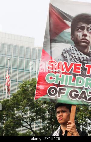 GIACARTA, INDONESIA - 1° GIUGNO: Un manifestante pro-palestinese regge un cartello con la scritta "Save the Children of Gaza” durante la manifestazione pro-palestinese presso l'ambasciata statunitense di fronte a Giacarta, Indonesia, il 1° giugno 2024. La manifestazione ha protestato contro l'attacco militare israeliano a Rafah, Gaza. Foto Stock