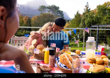 Un gruppo di amici che abbracciano e cenano con le bandiere degli stati uniti Foto Stock