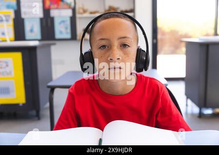 Il ragazzo birazziale studia intensamente a scuola con una videochiamata Foto Stock