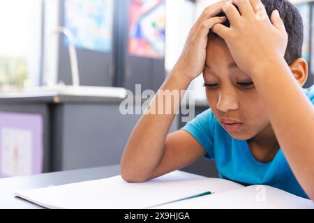 Ragazzo birazziale che studia duramente in classe a scuola, con spazio di copia Foto Stock