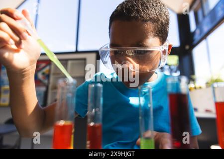 Il ragazzo birazziale esplora gli esperimenti scientifici a scuola in classe Foto Stock