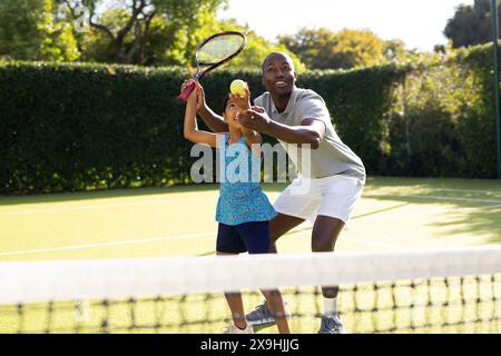 All'aperto, padre e figlia diversi giocano a tennis nelle giornate di sole Foto Stock