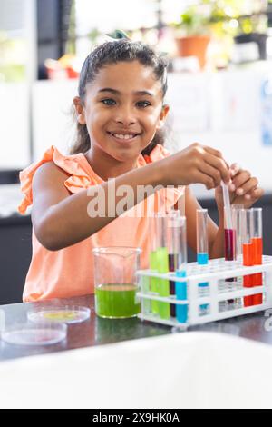 A scuola, una giovane studentessa birazziale sta conducendo un esperimento scientifico Foto Stock