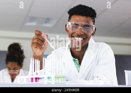 Un ragazzo birazziale adolescente conduce un esperimento in un laboratorio delle superiori Foto Stock