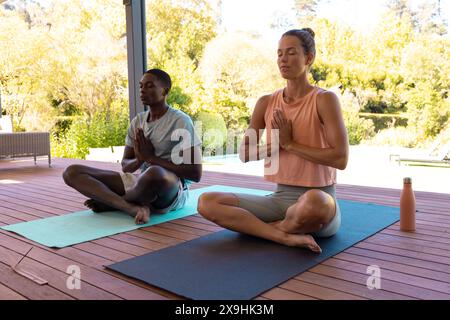 Una giovane coppia diversificata che meditava fuori, trovando la pace insieme Foto Stock