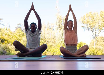 Una coppia giovane e variegata che pratica yoga all'aperto Foto Stock