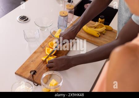 Una coppia variegata a casa che prepara la colazione e si diverte ad attività culinarie mattutine Foto Stock