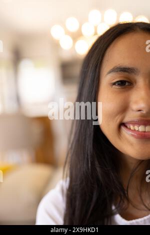 Una giovane ragazza birazziale che indossa una camicia bianca, sorride a casa, copia spazio Foto Stock