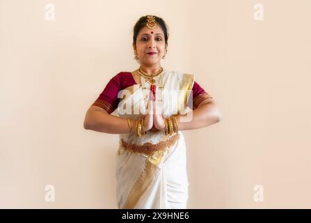 Ballerina classica indiana che dimostra la postura della danza classica di Bharatanatyam su sfondo chiaro Foto Stock