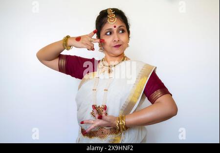 Ballerina classica indiana che dimostra la postura della danza classica di Bharatanatyam su sfondo chiaro Foto Stock