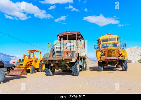 Nelson, Nevada - 15 aprile 2024: Massicci camion e bulldozer per impieghi gravosi di vecchia scuola nel mezzo del deserto sotto un cielo azzurro. Foto Stock