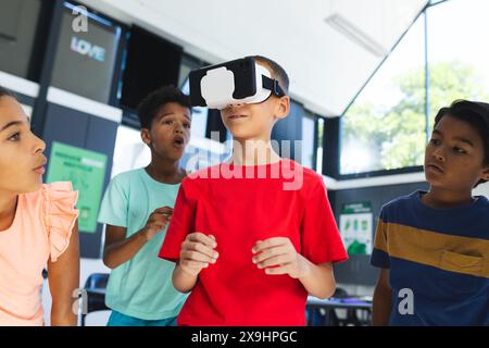 A scuola, diversi gruppi di giovani studenti stanno esplorando la realtà virtuale Foto Stock