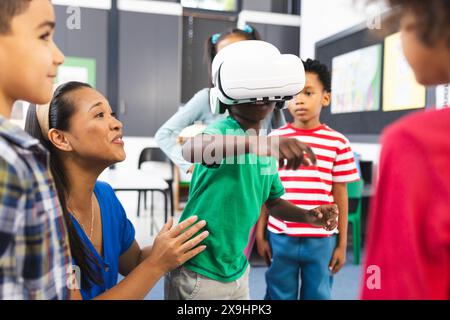 A scuola, diversi gruppi di studenti esplorano la realtà virtuale con il loro insegnante Foto Stock