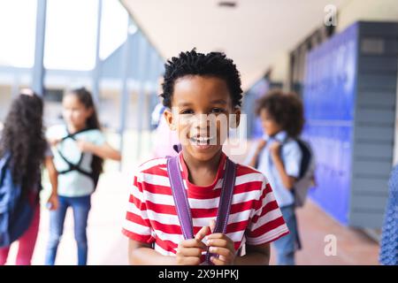 Giovane ragazzo afroamericano sorridente con il suo zaino all'aperto a scuola Foto Stock