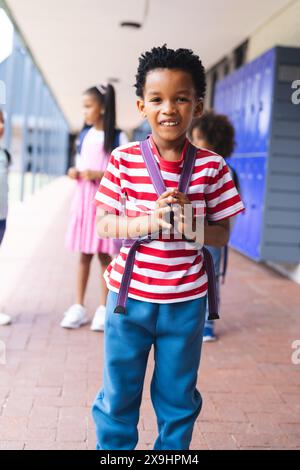 A scuola, il giovane afroamericano sta in piedi, sorridendo all'aperto Foto Stock