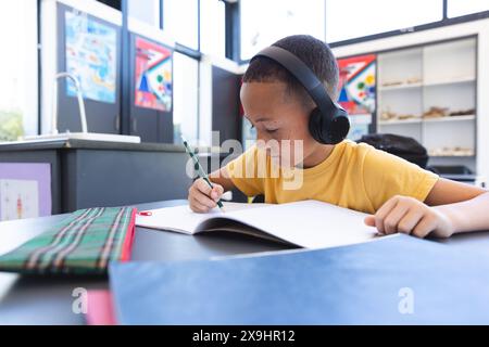 Il ragazzo birazziale si concentra sul lavoro scolastico a scuola Foto Stock