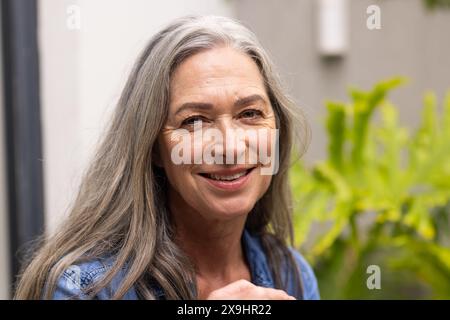 A casa, donne birazziali senior di mezza età con lunghi capelli grigi e rughe sorridenti all'aperto Foto Stock