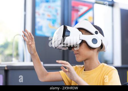 Birazziale ragazzo esplora la realtà virtuale a scuola Foto Stock