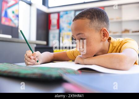 Il ragazzo birazziale si concentra sul lavoro scolastico a scuola Foto Stock