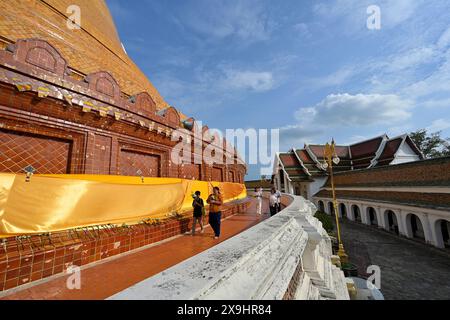 Persone che trasportano offerte, circumambulando il percorso interno intorno al chiostro circolare del gigantesco stupa Phra Pathom Chedi, Nakhon Pathom Foto Stock
