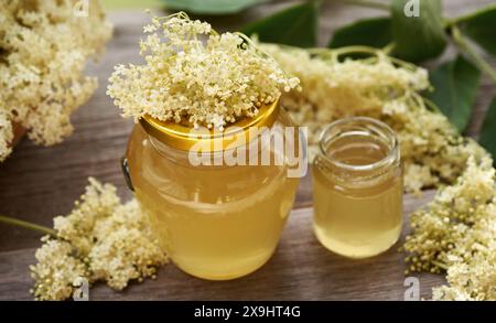 Due vasetti di vetro di sciroppo di fiori di sambuco fatto in casa su un tavolo di legno Foto Stock