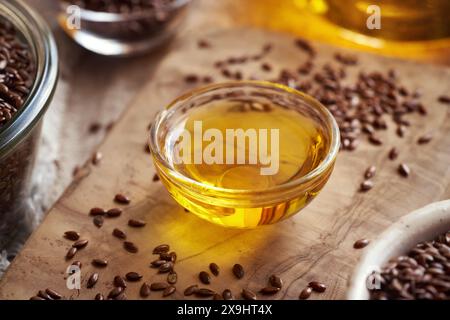 Semi di lino su un tavolo con un recipiente di olio di semi di lino, da vicino Foto Stock