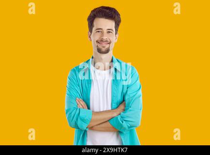 Ritratto di un giovane uomo attraente sorridente in abiti casual che posa su sfondo arancione. Foto Stock