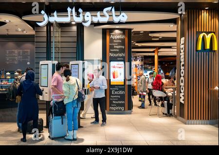 I passeggeri dei voli sono visti al ristorante fast-food americano McDonald's, catena all'aeroporto internazionale di Dubai, Emirati Arabi Uniti. Foto Stock