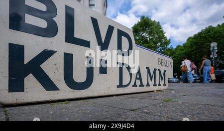 31 maggio 2024, Berlino: Un elemento di seduta in cemento con l'iscrizione "BLVD Ku'damm Berlin" si trova all'incrocio tra Kurfürstendamm e Uhlandstraße. Kurfürstendamm, conosciuta anche come Ku'damm, è una delle più grandi vie dello shopping di Berlino ed è considerata un punto di riferimento della capitale. Foto: Monika Skolimowska/dpa Foto Stock